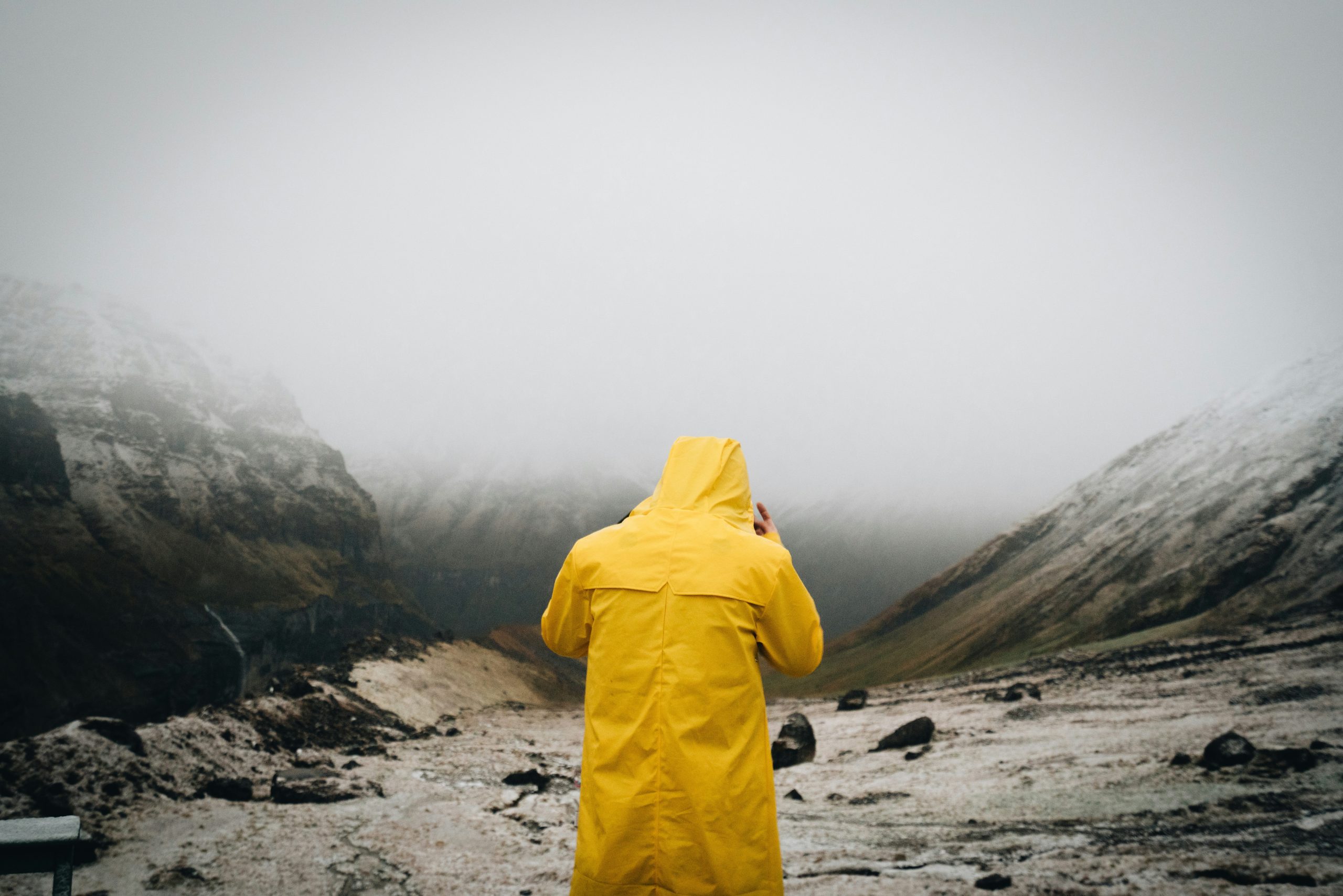 Hiker standing confidently amidst mountains during rainfall, thanks to proper gear.