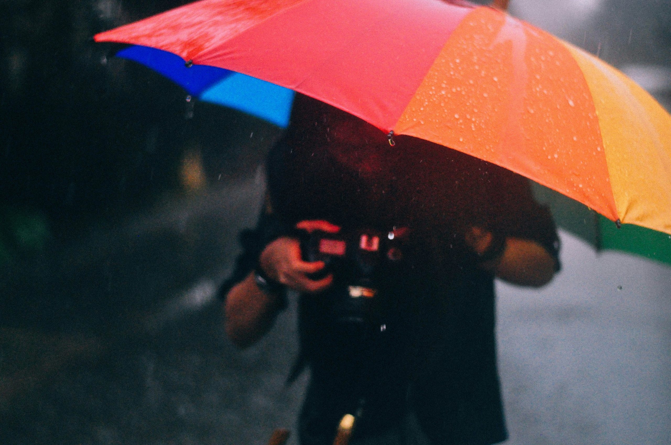 Smiling traveler holding a small backpack in heavy rain without getting wet